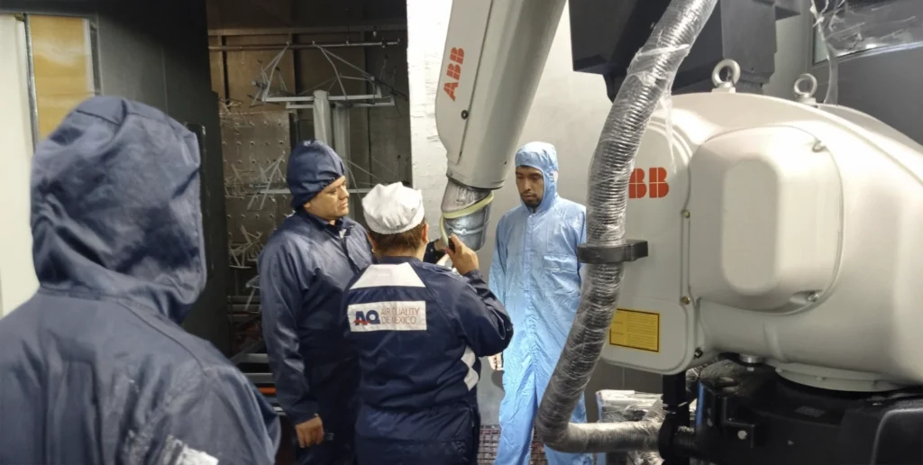 Equipo técnico de Air Quality de México realizando una inspección en una cabina de pintura automatizada con robot ABB, asegurando la correcta filtración de aire y calidad en el proceso.